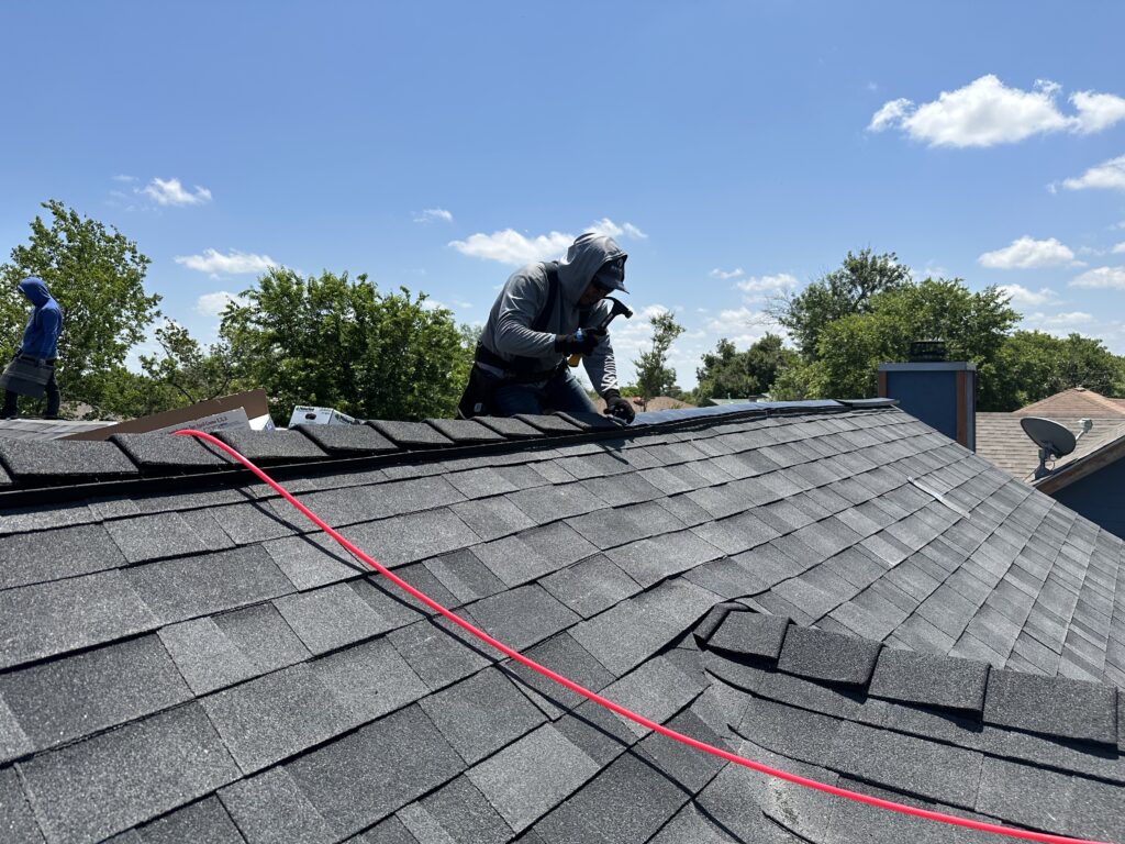 Dayton Contracting roof technician installing EZ Ridge XT ridge cap shingles over vented ridge.